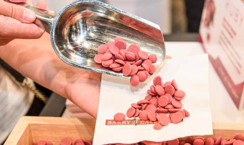 Ruby chocolate wafers being scooped into a napkin by a booth attendee